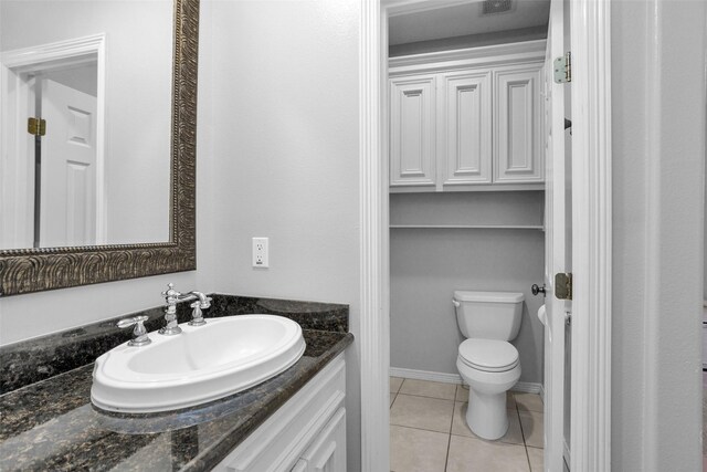 bathroom featuring baseboards, toilet, vanity, and tile patterned flooring