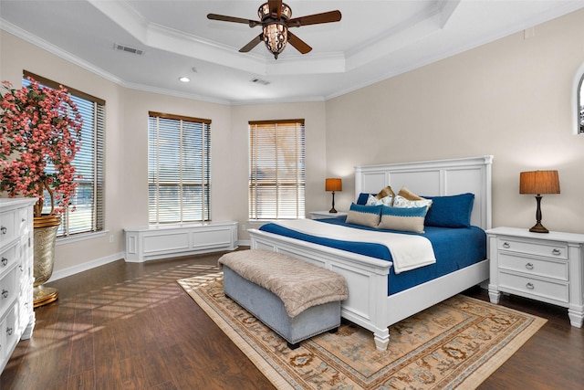 bedroom with a tray ceiling, crown molding, visible vents, and dark wood-style flooring