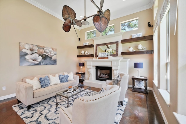 living area featuring a glass covered fireplace, baseboards, ornamental molding, and a towering ceiling