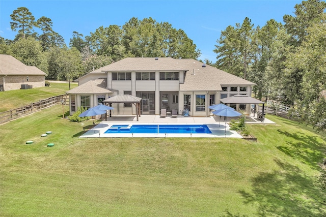 rear view of house with a gazebo, a lawn, and fence