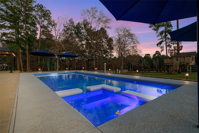 view of swimming pool with a patio area, a pool with connected hot tub, and a playground