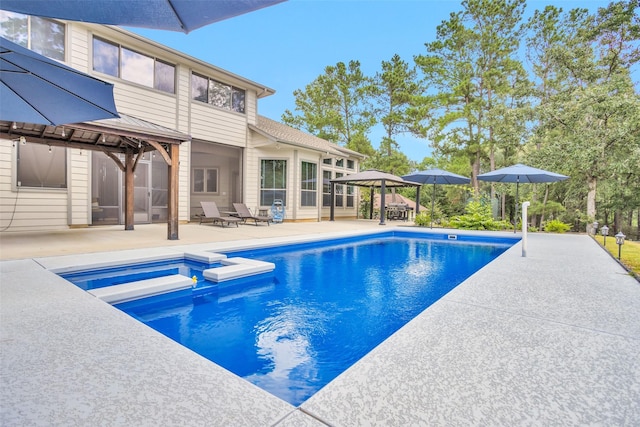 view of pool with a patio, a pool with connected hot tub, and a sunroom