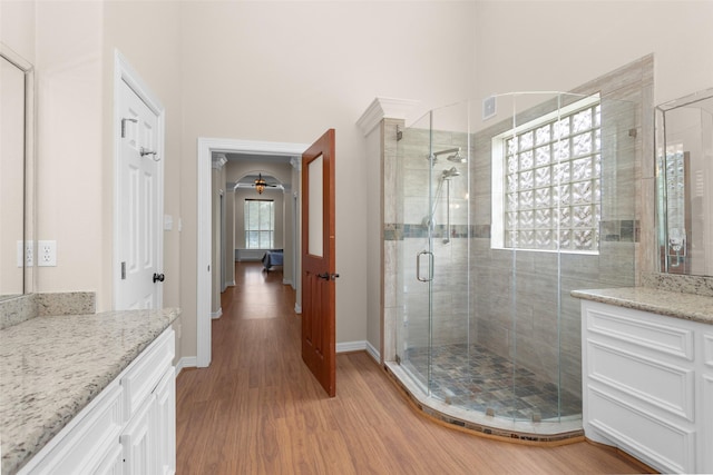 bathroom with baseboards, a shower stall, wood finished floors, and vanity