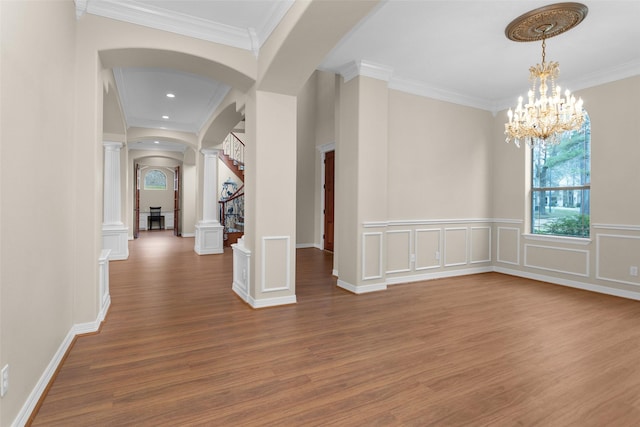 interior space featuring decorative columns, arched walkways, wood finished floors, and a decorative wall