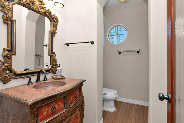 bathroom with baseboards, toilet, wood finished floors, and vanity