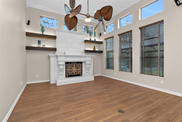 unfurnished living room with baseboards, wood finished floors, ornamental molding, and a high end fireplace