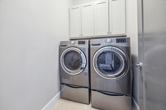 laundry room featuring light tile patterned floors, washer and clothes dryer, cabinet space, and baseboards