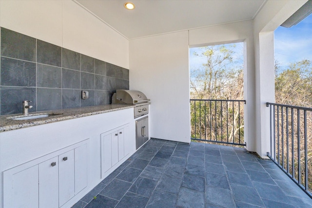 view of patio / terrace featuring a sink, a grill, a balcony, and an outdoor kitchen