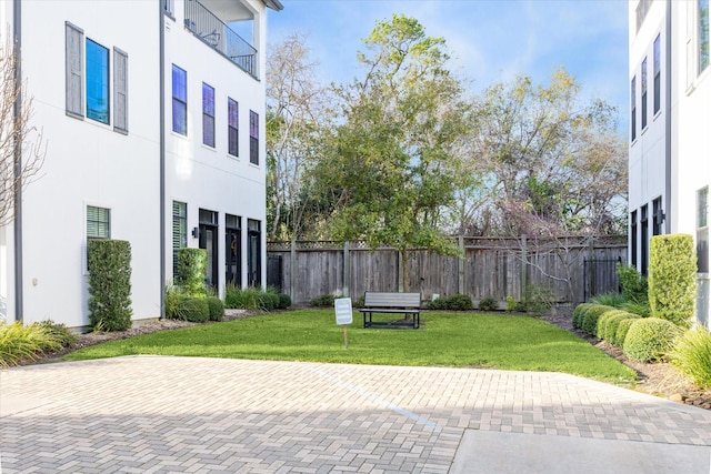 view of home's community with fence and a lawn