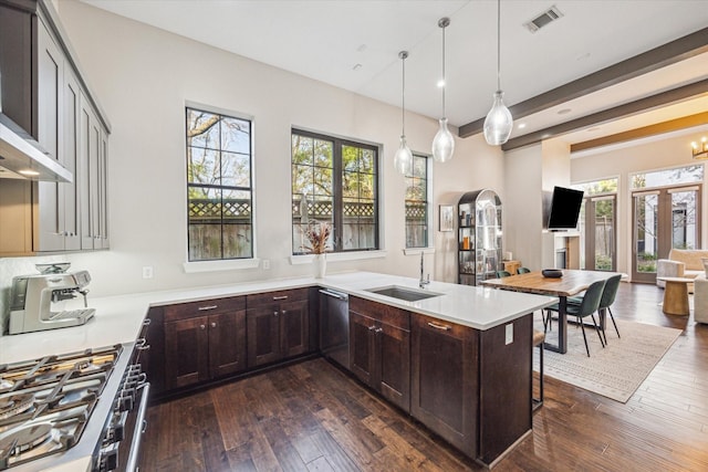 kitchen with stainless steel appliances, a sink, visible vents, light countertops, and dark wood finished floors