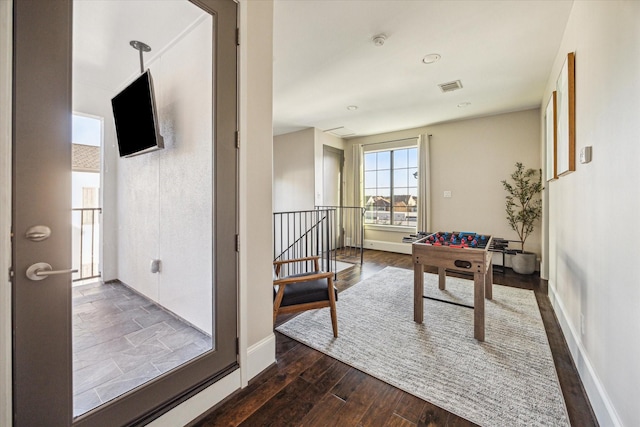 rec room featuring baseboards, visible vents, and dark wood finished floors