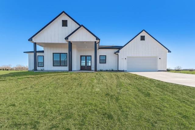 modern inspired farmhouse featuring an attached garage, concrete driveway, french doors, board and batten siding, and a front yard