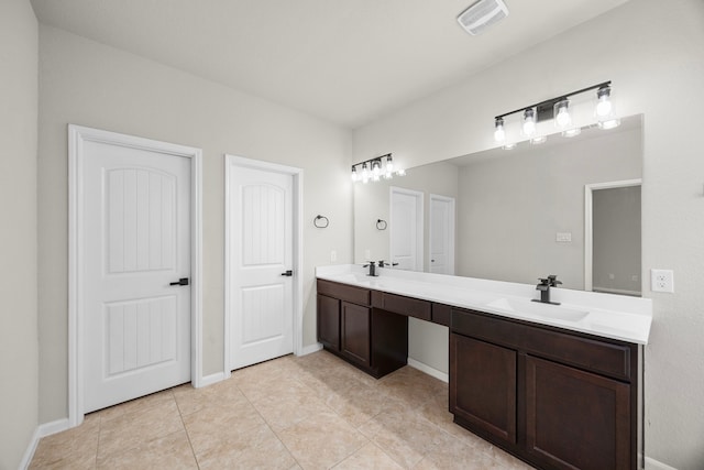 full bath featuring double vanity, visible vents, a sink, tile patterned flooring, and baseboards