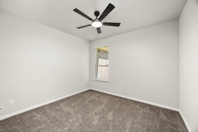 empty room with baseboards, dark carpet, and ceiling fan