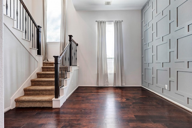 foyer entrance with hardwood / wood-style floors, stairs, baseboards, and visible vents