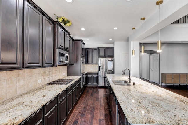 kitchen featuring a large island, stainless steel appliances, dark wood-style flooring, and a sink