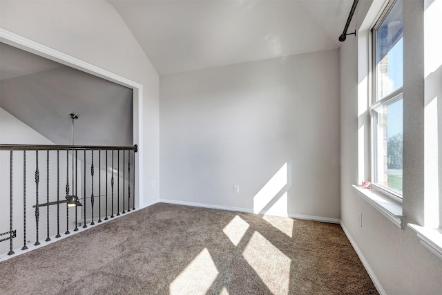 carpeted empty room with vaulted ceiling and baseboards