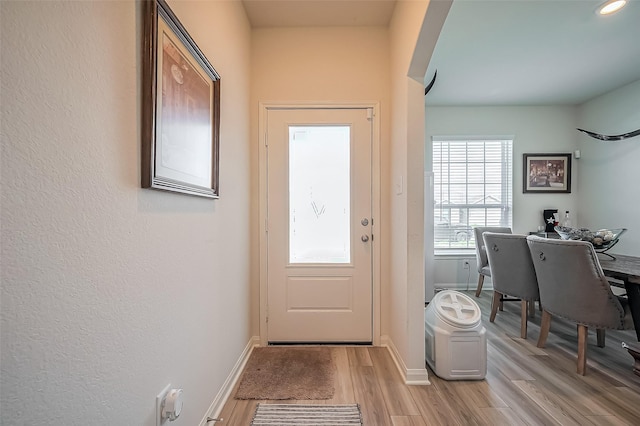 entryway with light wood-style floors, baseboards, and arched walkways