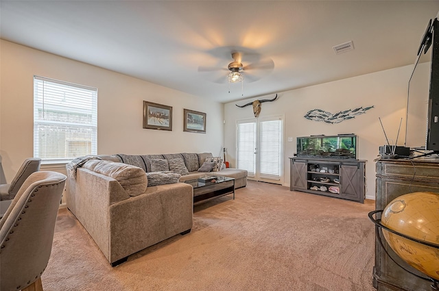 living area with light carpet, visible vents, and a ceiling fan