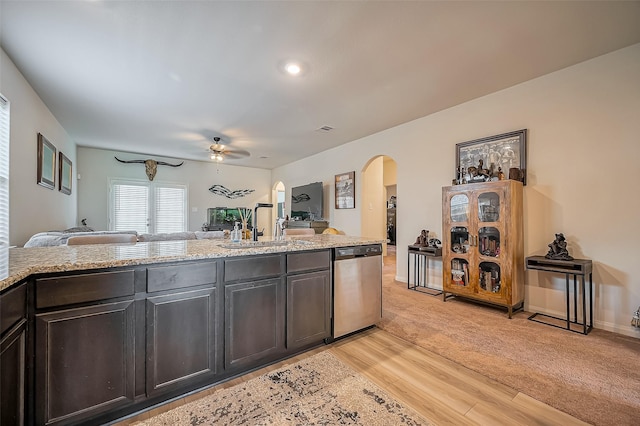 kitchen with arched walkways, a sink, light wood-style floors, open floor plan, and dishwasher