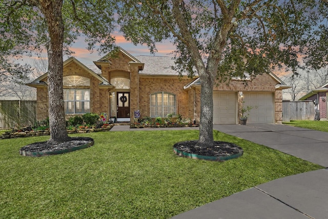 view of front of house with driveway, brick siding, fence, and a yard