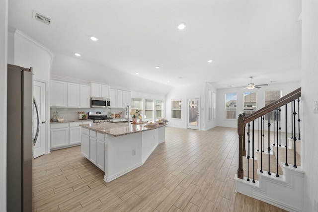 kitchen with light wood finished floors, stainless steel appliances, visible vents, a barn door, and a sink