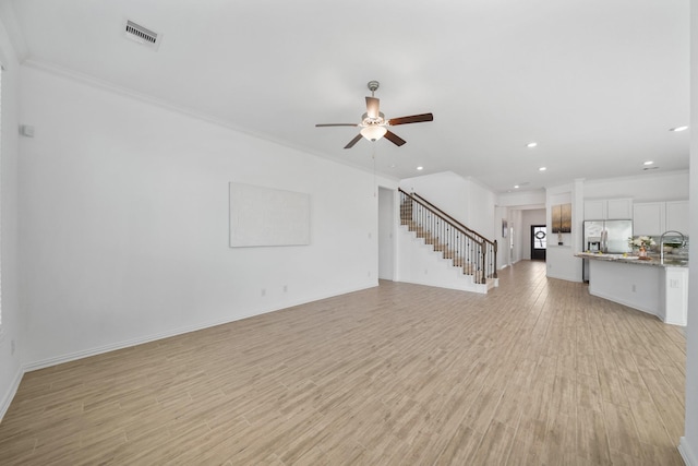 unfurnished living room with ornamental molding, visible vents, light wood finished floors, and stairs