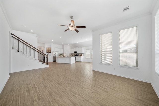 unfurnished living room featuring ceiling fan, recessed lighting, visible vents, stairs, and light wood finished floors