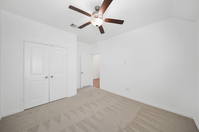 unfurnished bedroom with light carpet, visible vents, a ceiling fan, lofted ceiling, and a closet