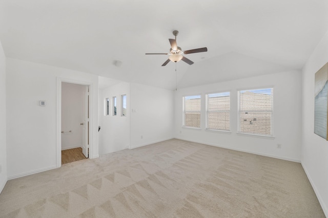 spare room with a ceiling fan, carpet flooring, vaulted ceiling, and baseboards