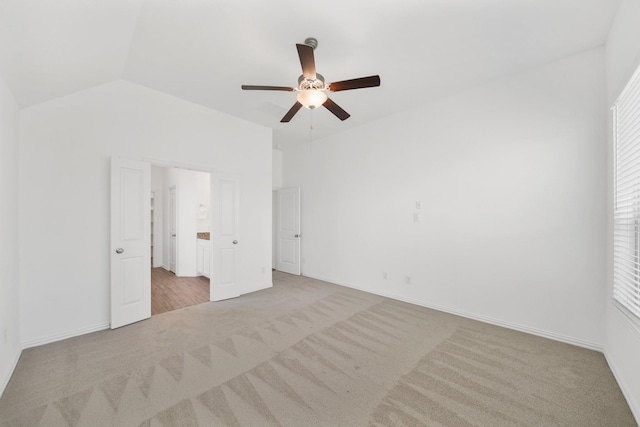 unfurnished bedroom featuring baseboards, connected bathroom, a ceiling fan, lofted ceiling, and carpet floors