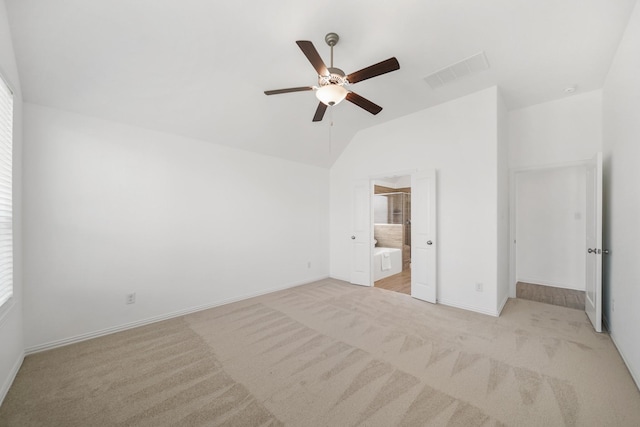 unfurnished bedroom with light colored carpet, visible vents, a ceiling fan, vaulted ceiling, and ensuite bath