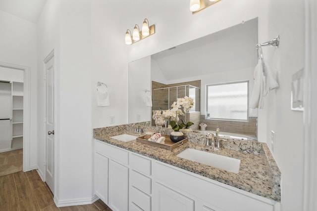 full bath with double vanity, a sink, a shower stall, and wood finished floors