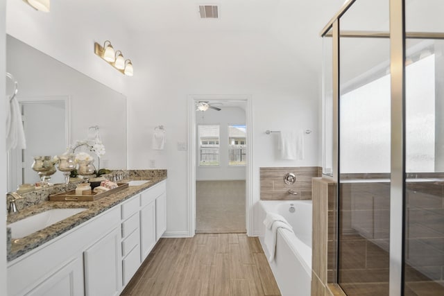 full bath with double vanity, visible vents, wood finished floors, a sink, and a bath