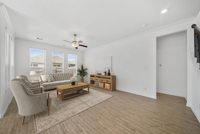 living area with light wood-style flooring, baseboards, ceiling fan, and crown molding