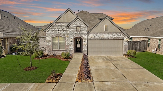 french country home featuring stucco siding, fence, concrete driveway, and a front yard