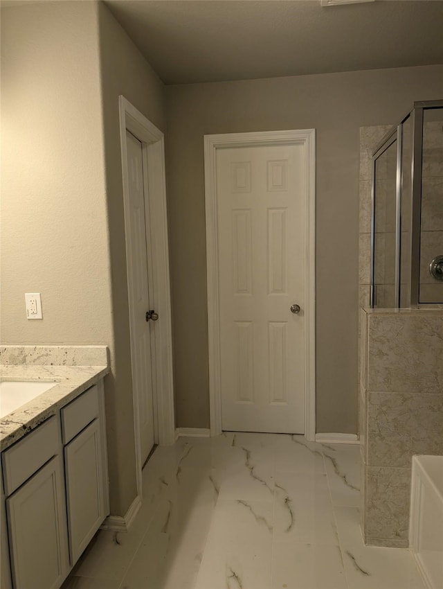 full bathroom with a tub to relax in, marble finish floor, a tile shower, vanity, and baseboards