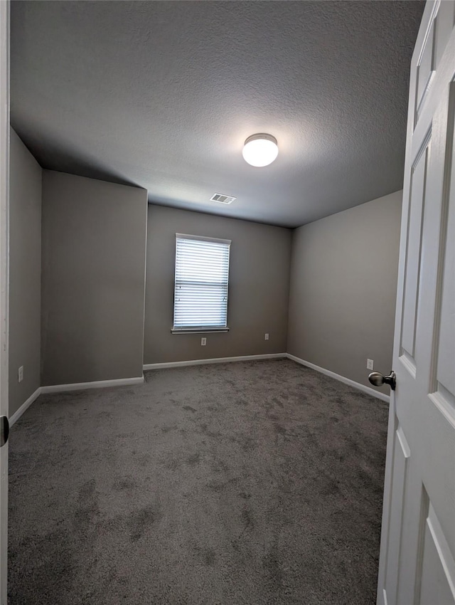 carpeted spare room with baseboards, visible vents, and a textured ceiling