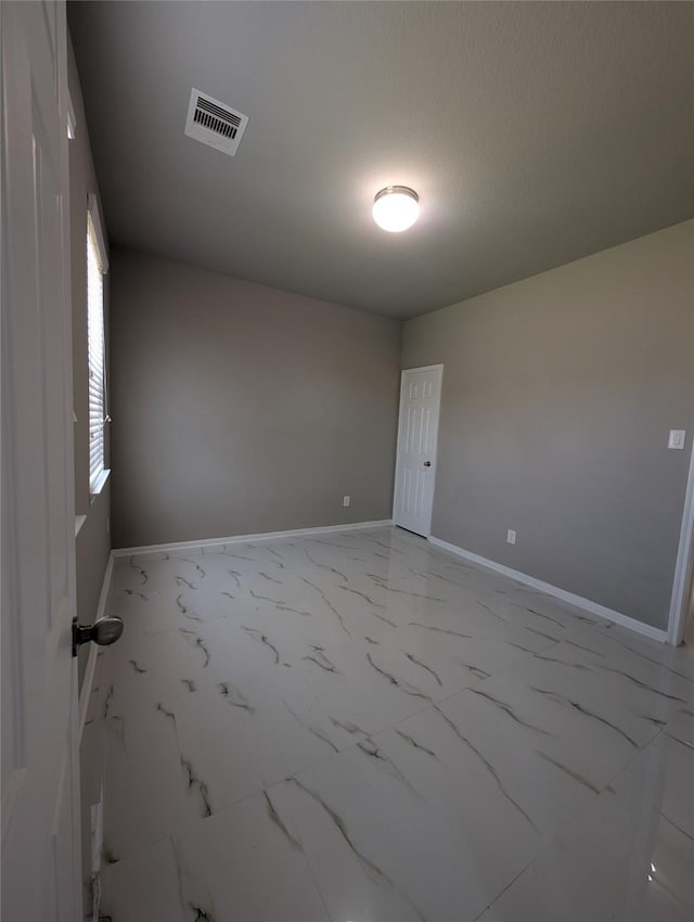 empty room with marble finish floor, baseboards, visible vents, and a textured ceiling