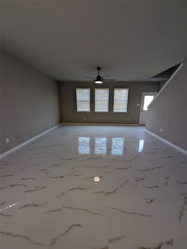 unfurnished room featuring marble finish floor, ceiling fan, and baseboards