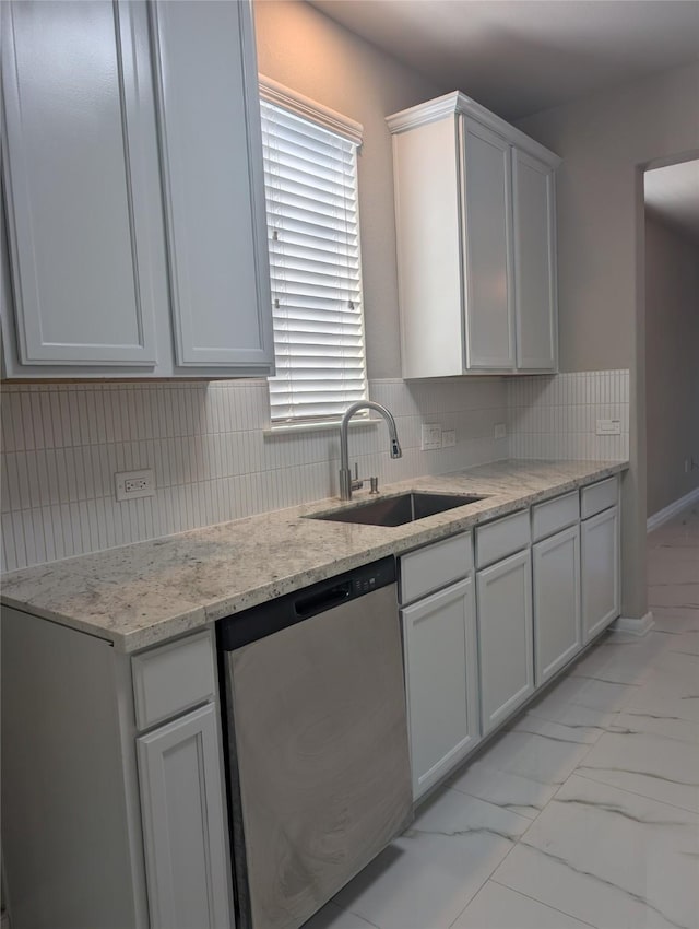 kitchen featuring backsplash, marble finish floor, light stone countertops, stainless steel dishwasher, and a sink