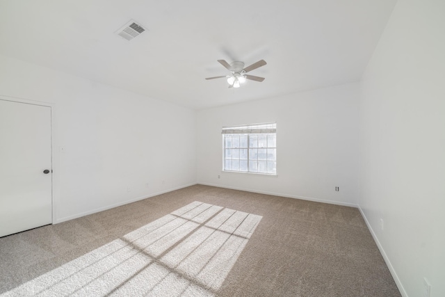 empty room with carpet floors, baseboards, visible vents, and ceiling fan