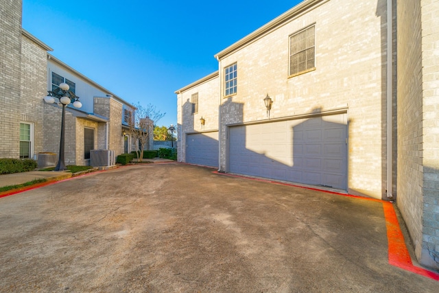 view of property exterior featuring a garage, central AC, and brick siding