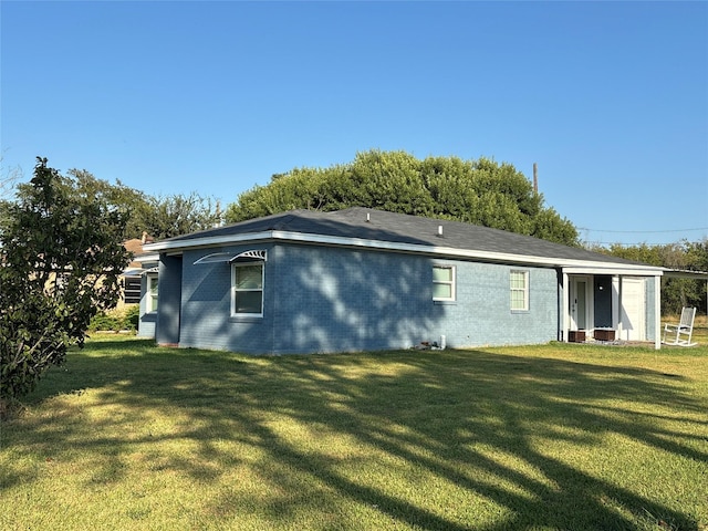 back of house with brick siding and a lawn