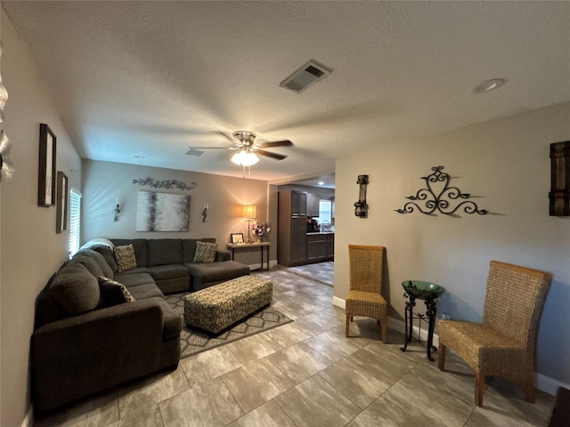 living area featuring visible vents, ceiling fan, a textured ceiling, and baseboards