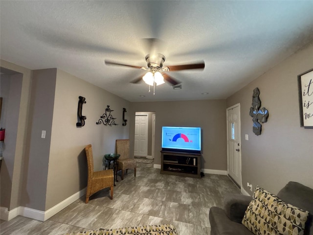 living area with visible vents, ceiling fan, a textured ceiling, and baseboards