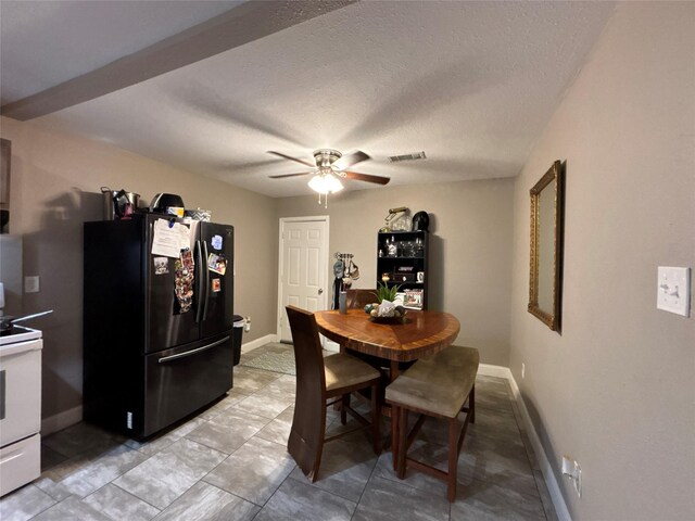 dining room featuring a textured ceiling, ceiling fan, visible vents, and baseboards