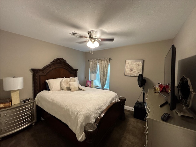 bedroom with a textured ceiling, dark colored carpet, and ceiling fan