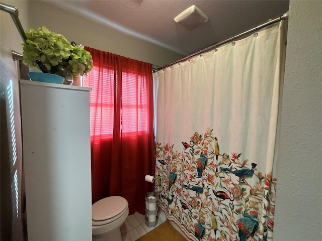 full bath featuring a textured ceiling, a textured wall, toilet, tile patterned floors, and a shower with curtain