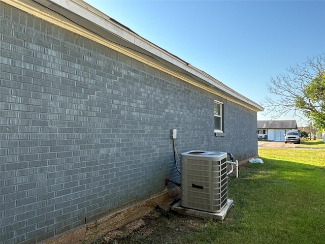 view of side of property featuring brick siding, a yard, and central air condition unit